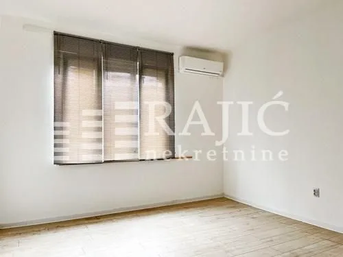 Empty room with a window and an air conditioner on the wall.