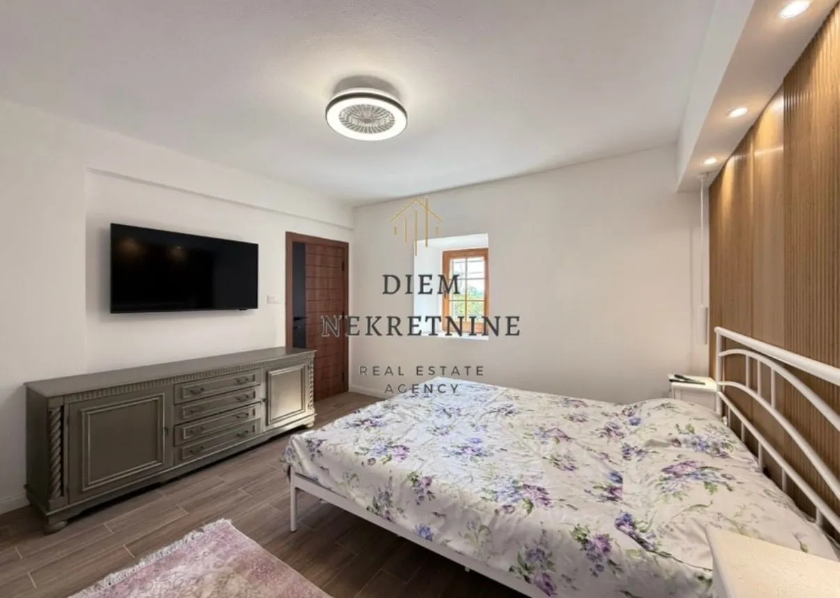 Furnished bedroom with a double bed, dresser, and television.