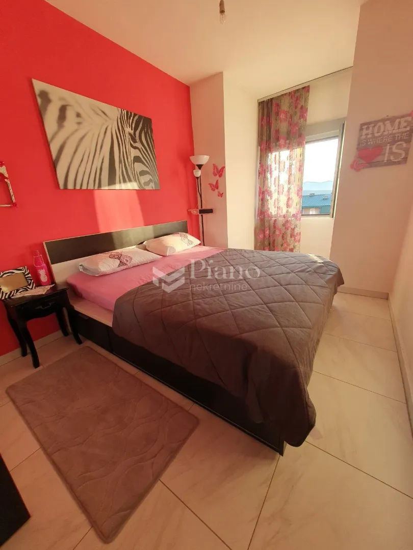 Furnished bedroom with a double bed and a red accent wall.