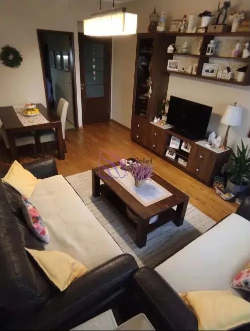 Dnevni boravak sa garniturom, TV komodom i trpezarijskim stolom.