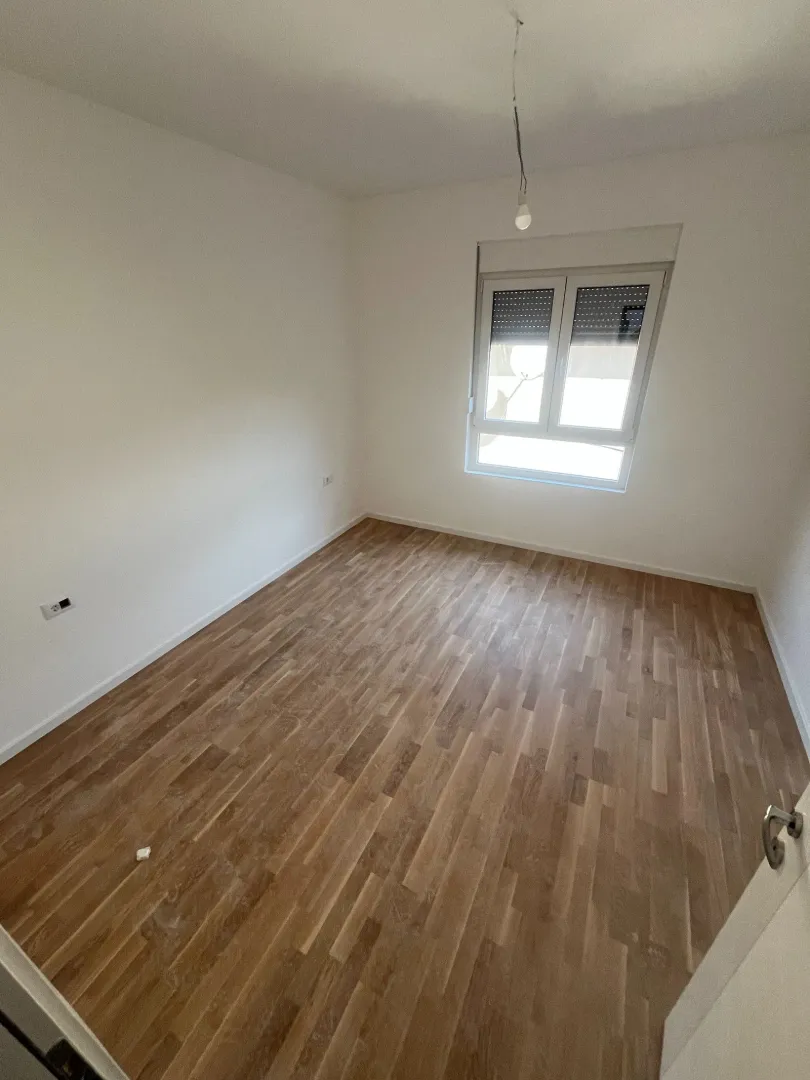 Prazna soba sa bijelim zidovima i drvenim podom.