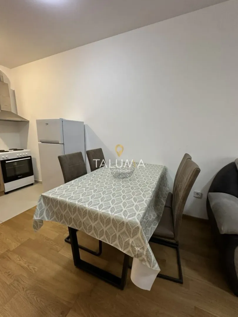 Dining table with chairs in the living room with the kitchen in the background.