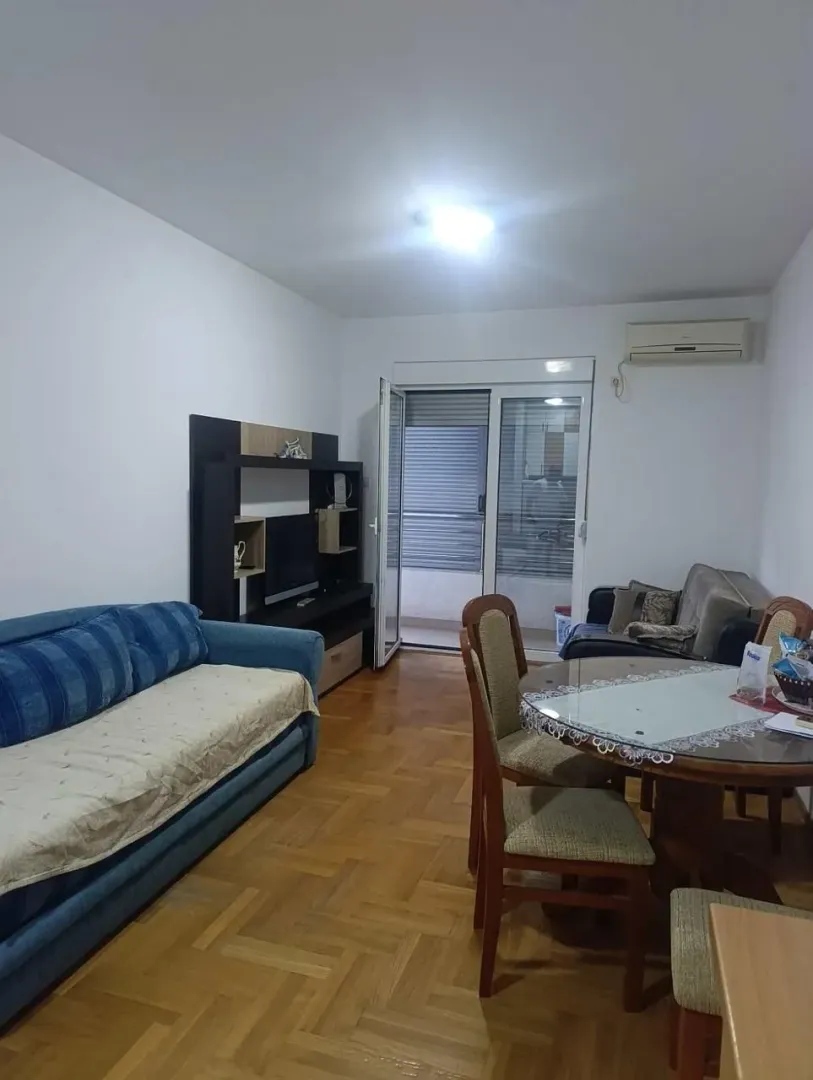 Dnevna soba sa garniturom, trpezarijskim stolom i izlazom na terasu.