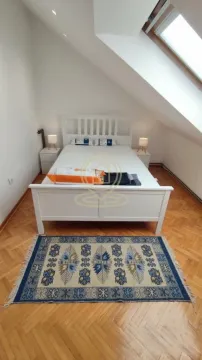 Potkrovna spavaća soba sa belim krevetom i krovnim prozorom. - image 8