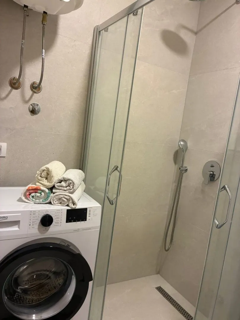 Modern bathroom with a shower cabin and washing machine.