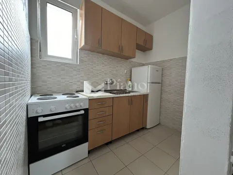 Small kitchen with wooden units, cooker and refrigerator. - image 3