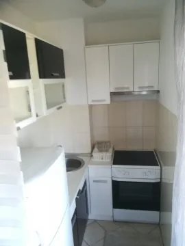 Mala i funkcionalna kuhinja sa bijelim elementima i šporetom. - image 4