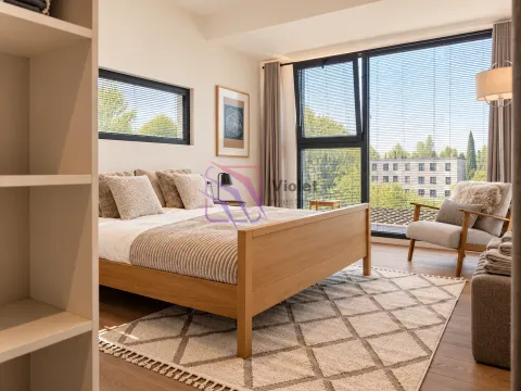 Spacious bedroom with a double bed, armchair, and large windows. - image 3