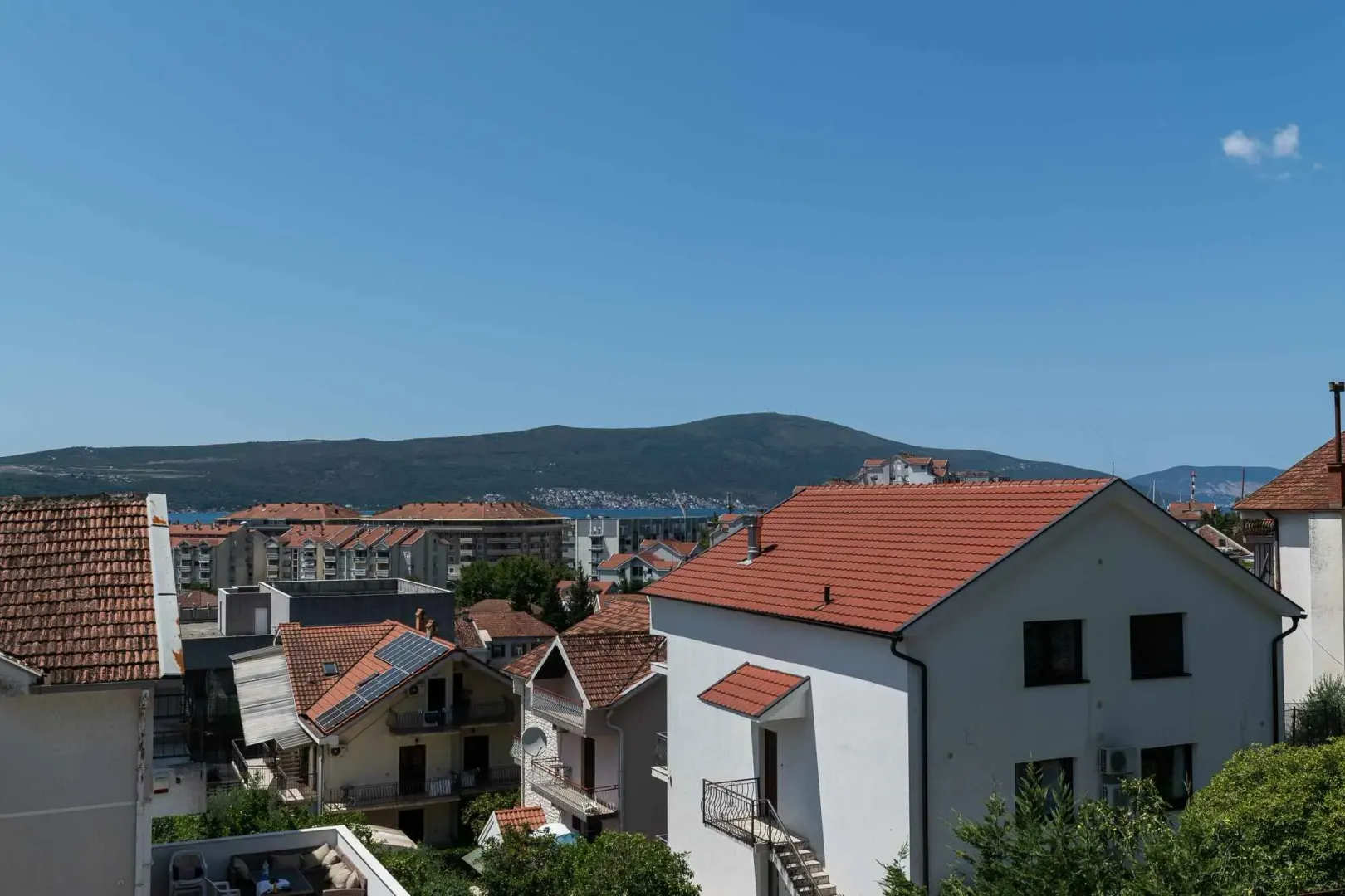 Pogled na okolne krovove kuća i brda u daljini.