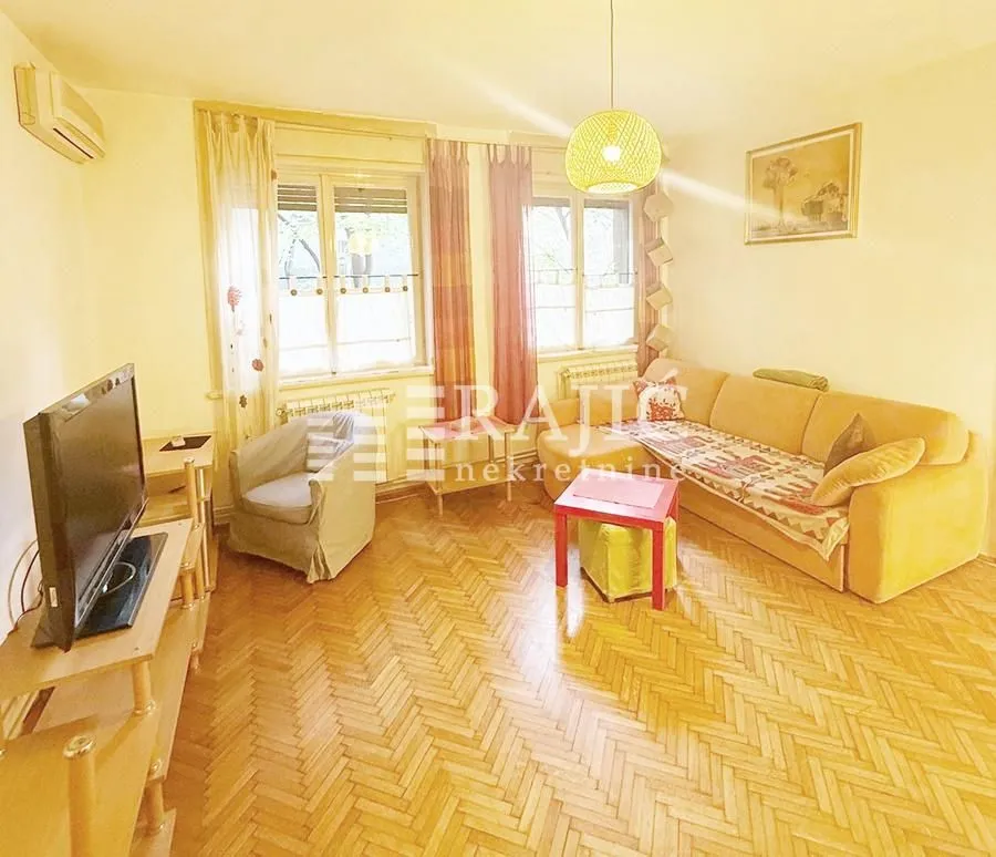 Living room with sofa, television, and parquet flooring.