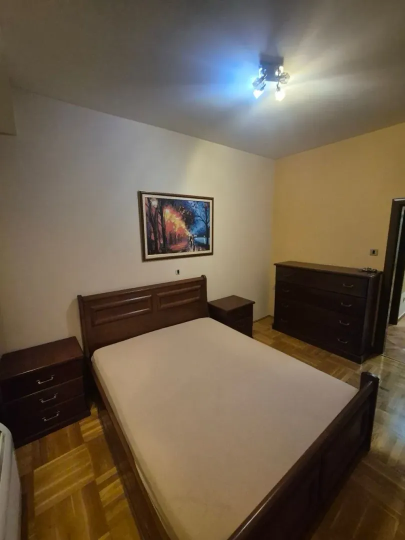 Spavaća soba sa bračnim krevetom, noćnim stočićima i komodom.