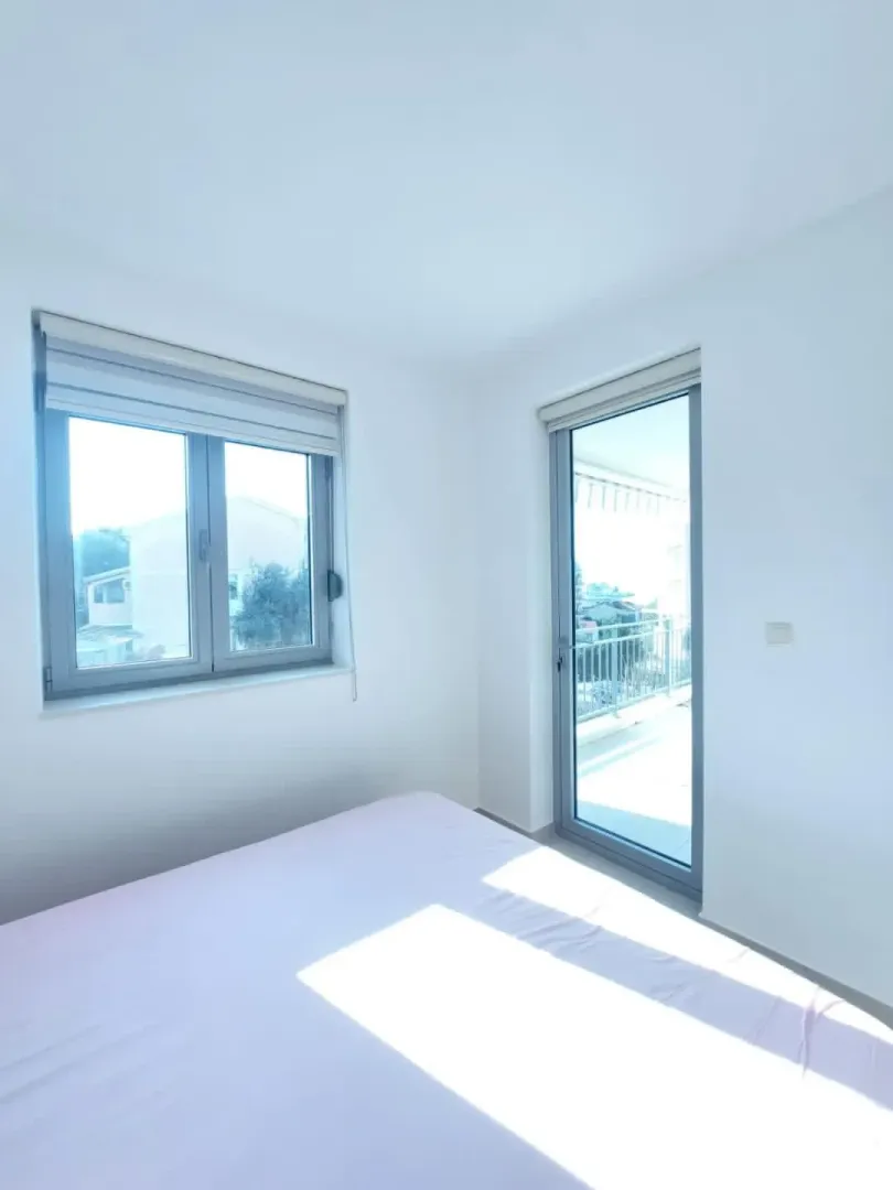 Bright bedroom with a bed, window, and terrace access.