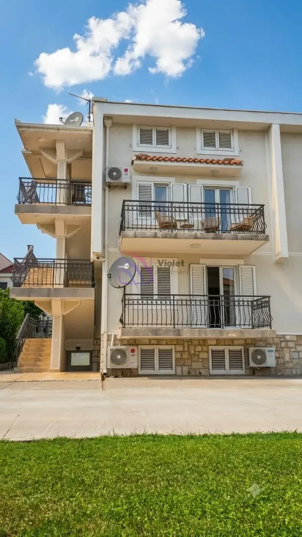 Exterior view of a three-story residential building with balconies and external stairs.