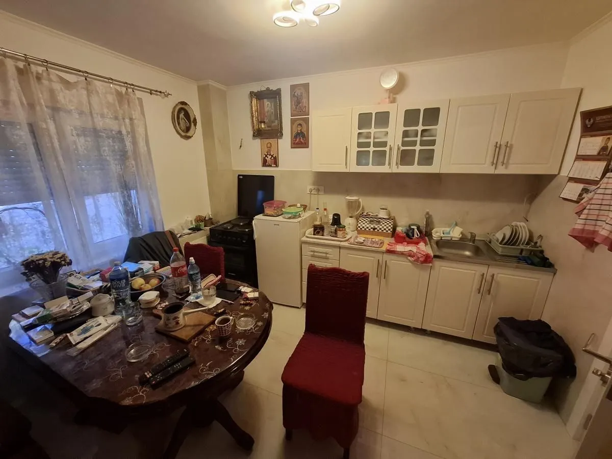 Manja kuhinja sa trpezarijskim stolom i belim elementima.