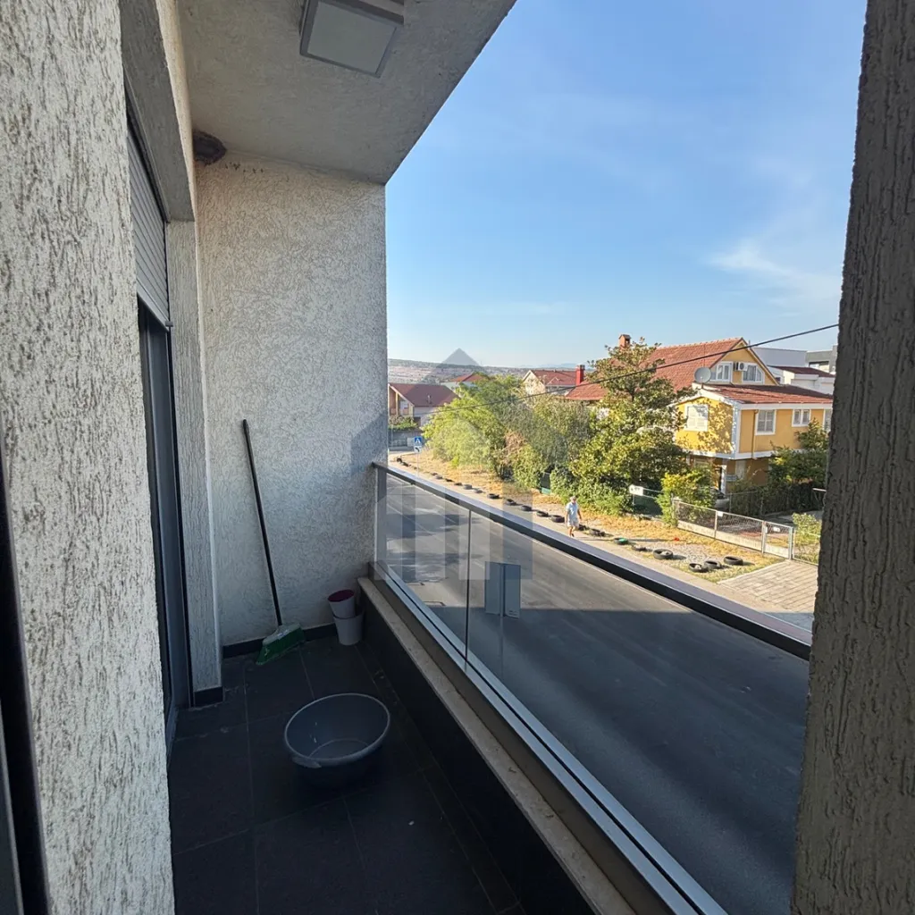 Small balcony with a glass railing and a view of the street and neighborhood.