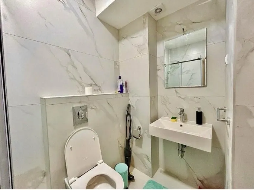 Small bathroom with marble tiles, sink, and toilet.