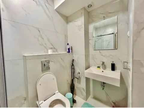 Small bathroom with marble tiles, sink, and toilet. - image 8