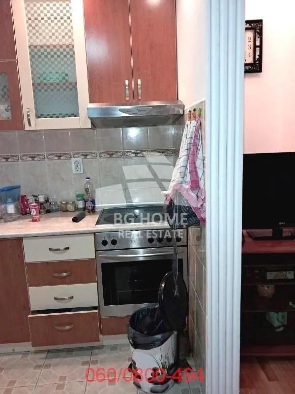 Manja kuhinja sa drvenim elementima, šporetom i aspiratorom.