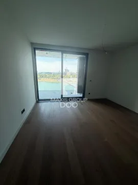 Prazna soba sa drvenim podom i velikim balkonskim vratima sa pogledom na reku. - image 6