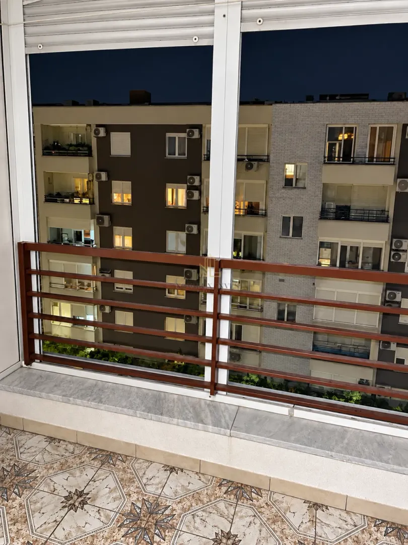 View from the glazed balcony overlooking neighboring buildings at night.