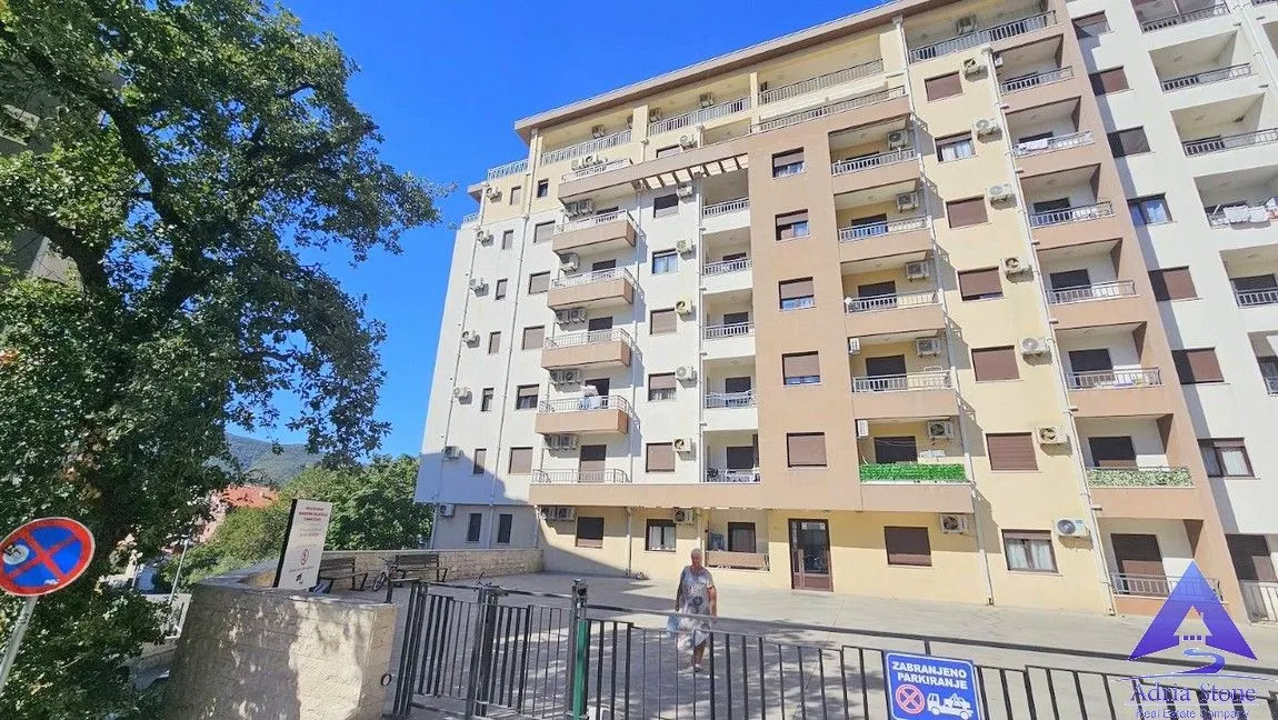 Pogled na spoljašnjost stambene zgrade sa ulazom i dvorištem.