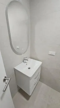 Savremeno opremljeno kupatilo sa umivaonikom, ogledalom i pločicama u neutralnim tonovima. - image 8