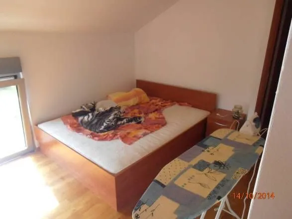 Manja spavaća soba sa bračnim krevetom i daskom za peglanje.