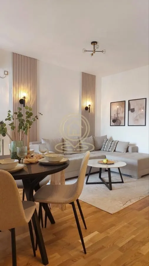 Dnevni boravak sa garniturom, trpezarijskim stolom i modernim zidnim oblogama.