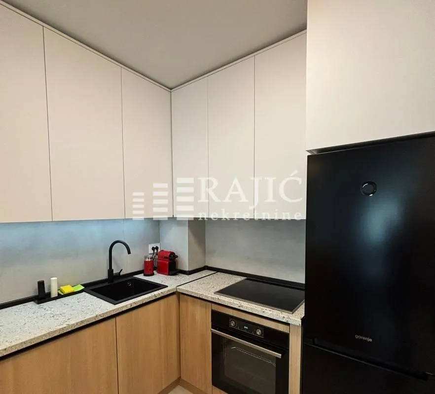 Modern kitchen with white cabinetry, built-in oven, and a black refrigerator.