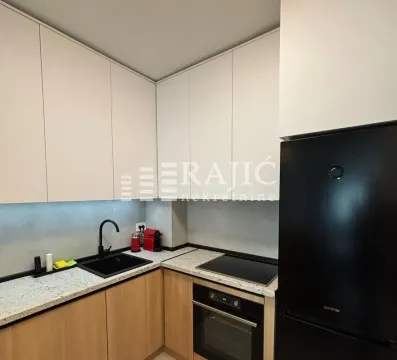 Modern kitchen with white cabinetry, built-in oven, and a black refrigerator. - image 7