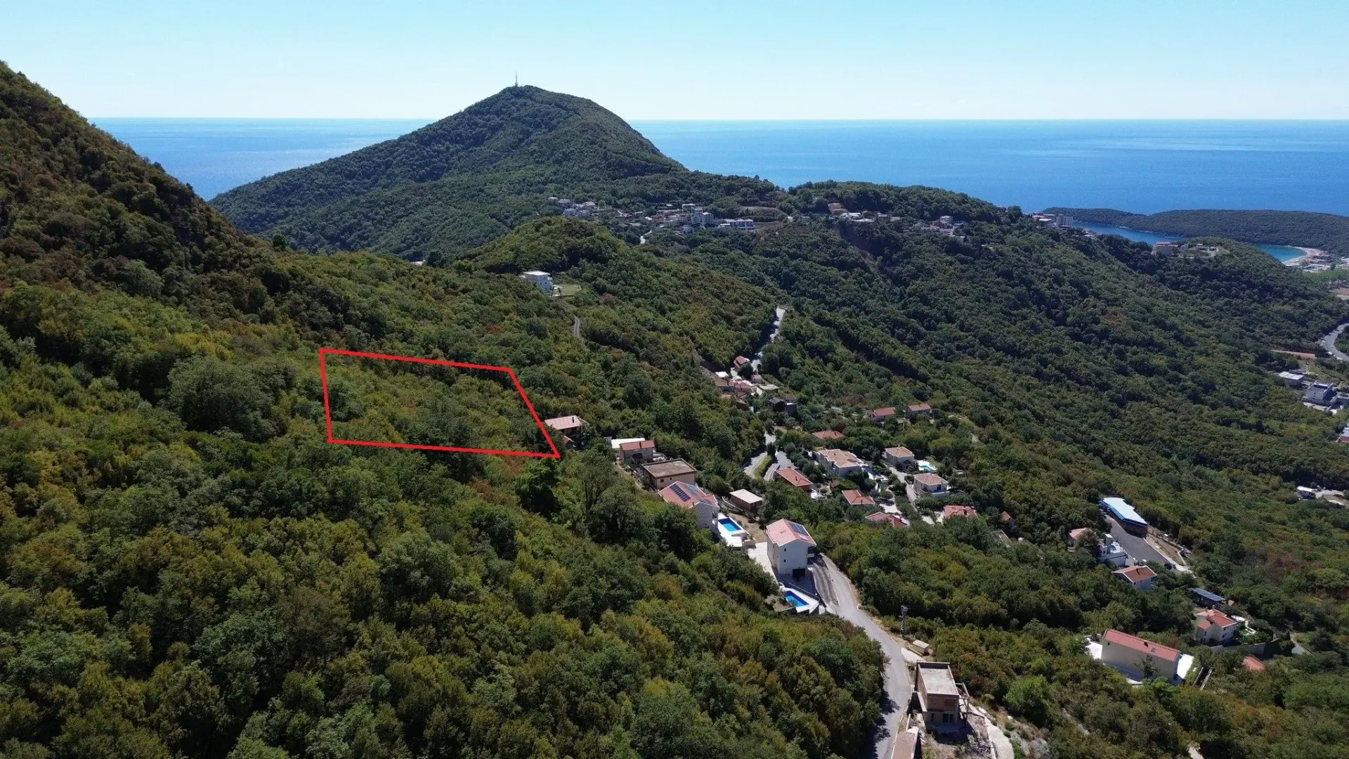 Vazdušni snimak terena sa označenom lokacijom parcele na šumovitom brdu sa pogledom na more.