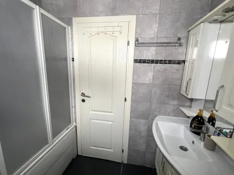 Bathroom with a shower cabin, washbasin, and white fixtures. - image 5