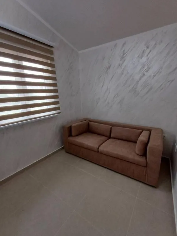 Smaller living room with a sofa and a window with blinds.