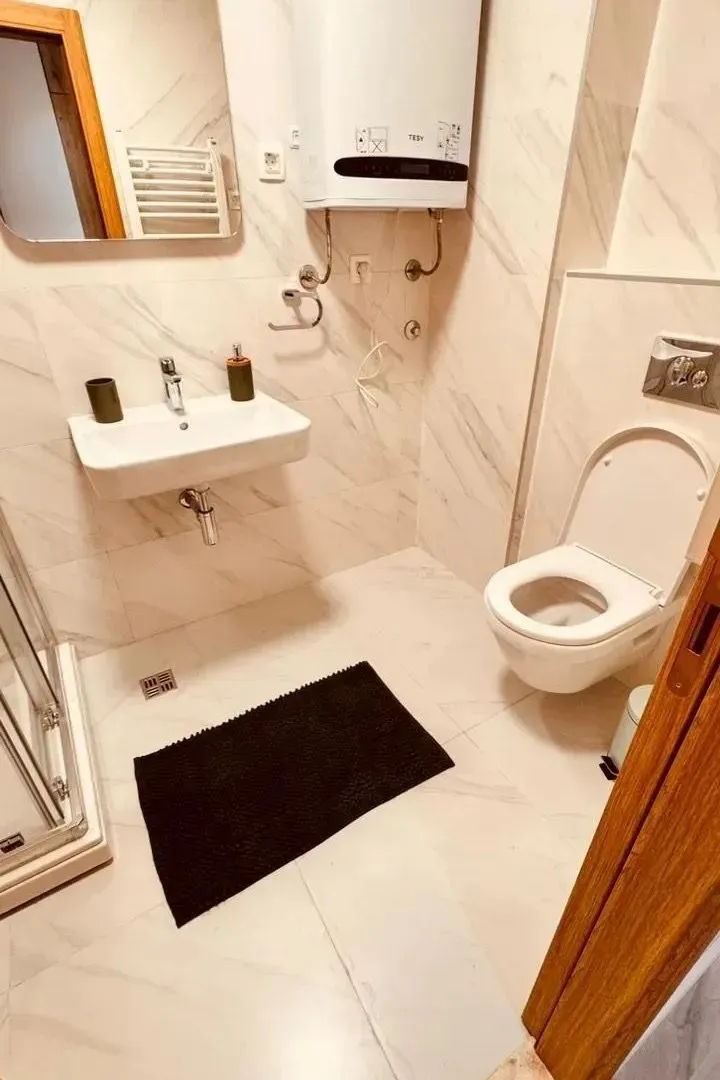 Moderno opremljeno kupatilo sa bijelim pločicama, umivaonikom i wc šoljom.