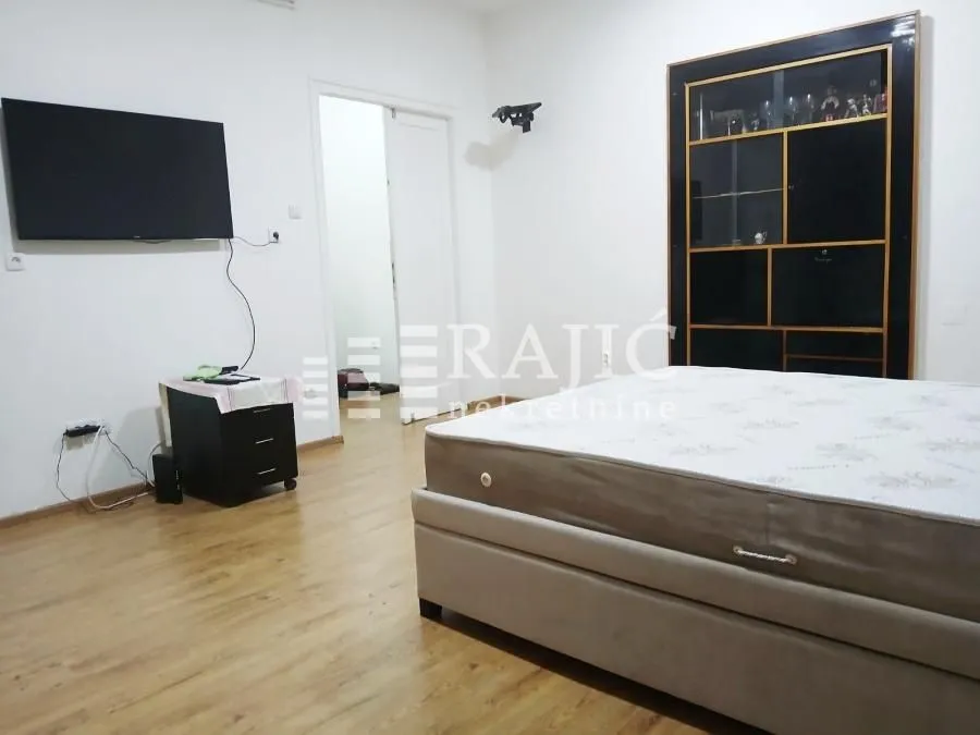 Furnished bedroom with a large double bed and a wall-mounted TV.