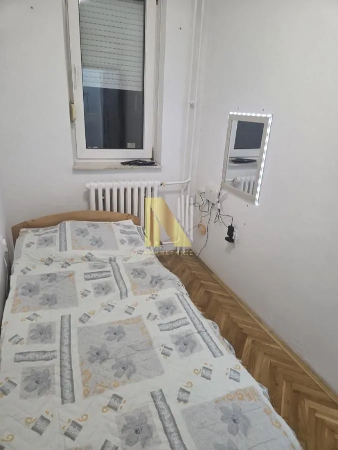 Manja spavaća soba sa krevetom i prozorom.