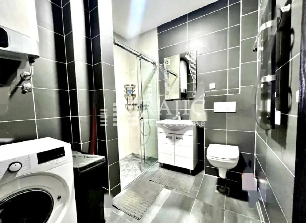 Modernly equipped bathroom with a shower cabin and washing machine.