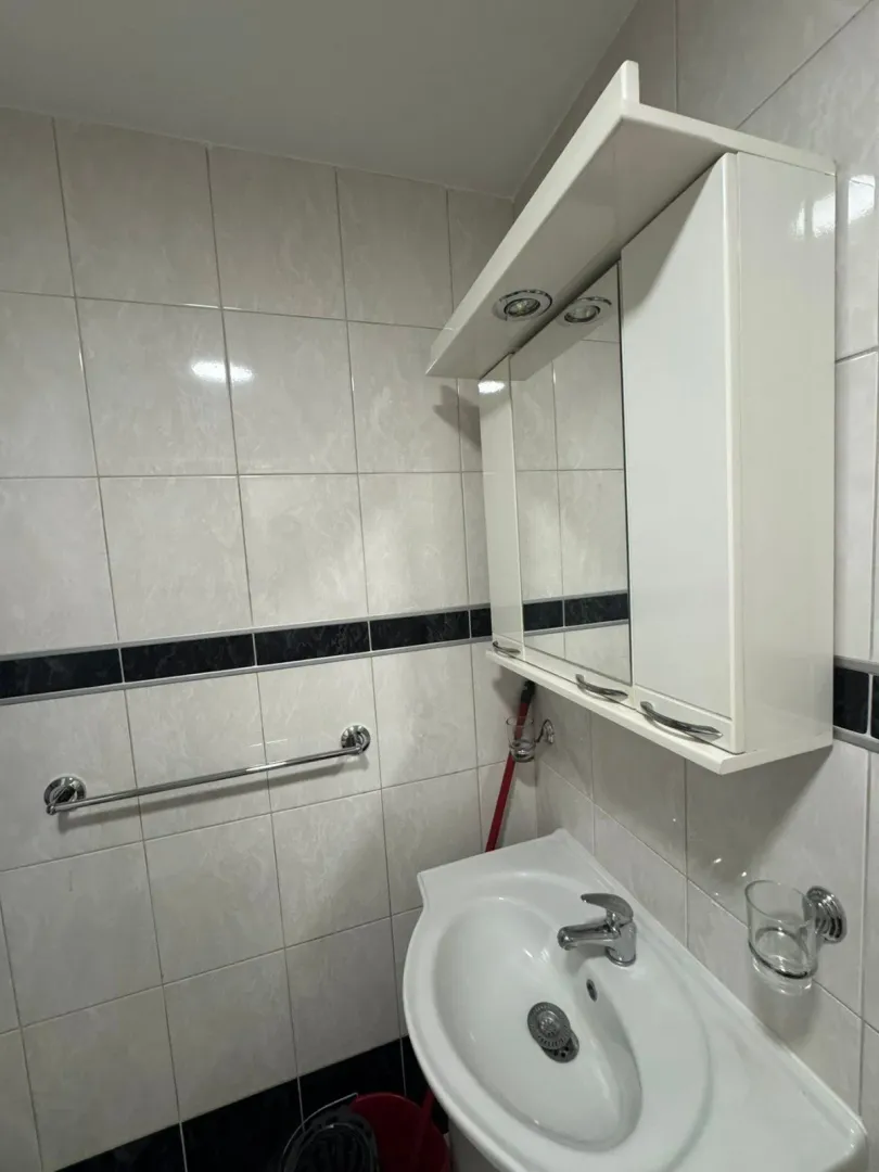 Bathroom with sink, mirror, and wall tiles.