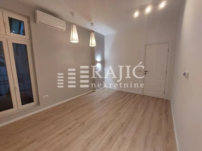 Empty room with laminate flooring, white walls, and an air conditioner.
