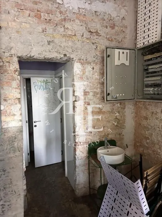 View of a room under renovation featuring exposed brick walls and a small washbasin.