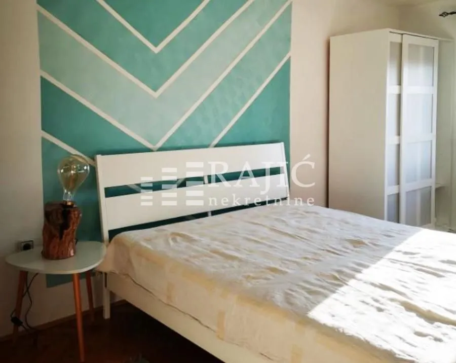 Furnished bedroom with a double bed and a decorative wall.