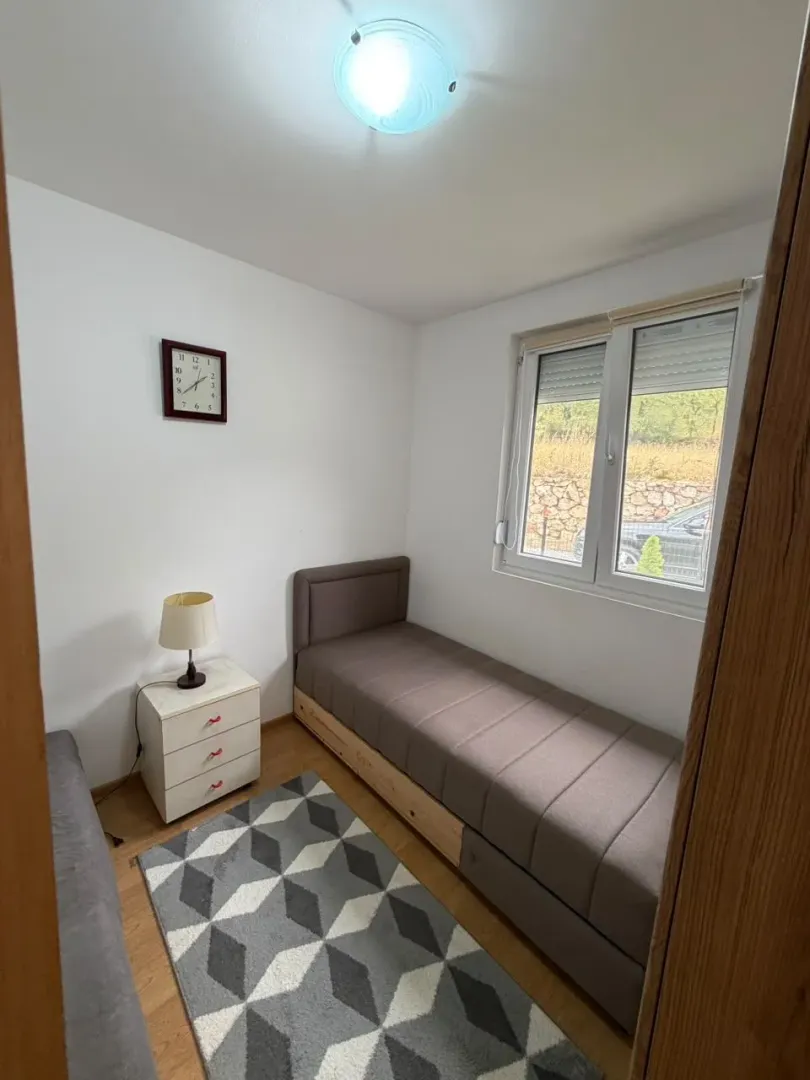Small bedroom with a bed, nightstand, and window.