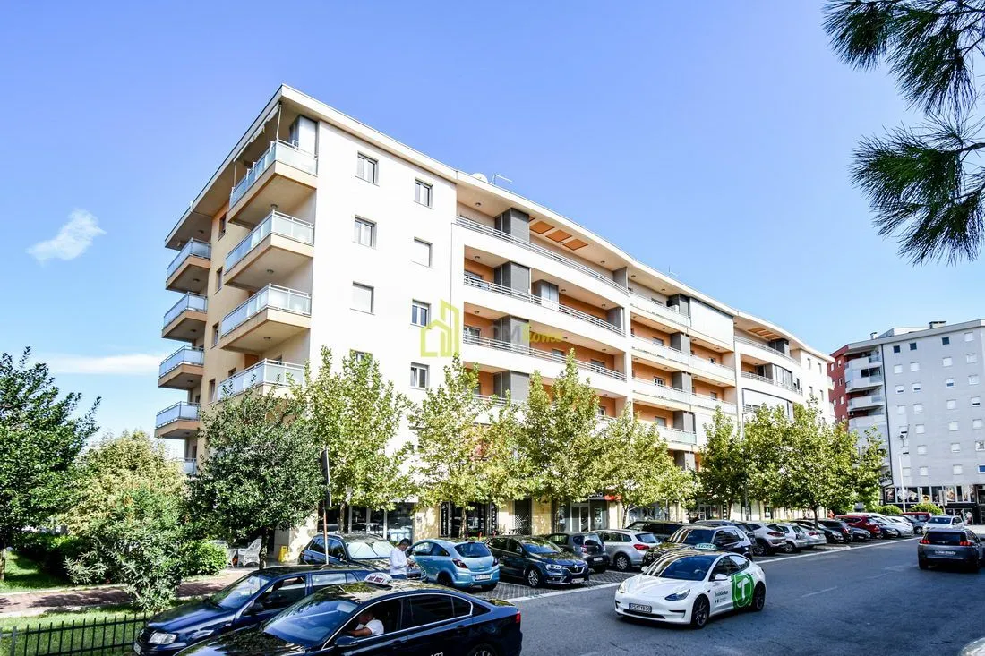 View of the residential building exterior with parking and surrounding greenery.