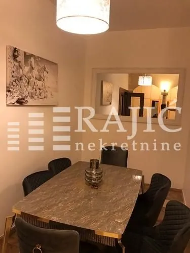 Trpezarija sa stolom, stolicama i velikim ogledalom na zidu.