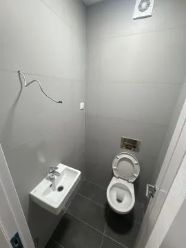 Manje kupatilo sa sijivim pločicama, toaletom i umivaonikom. - image 3