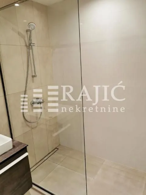 Modernly equipped bathroom with a walk-in shower and vanity.