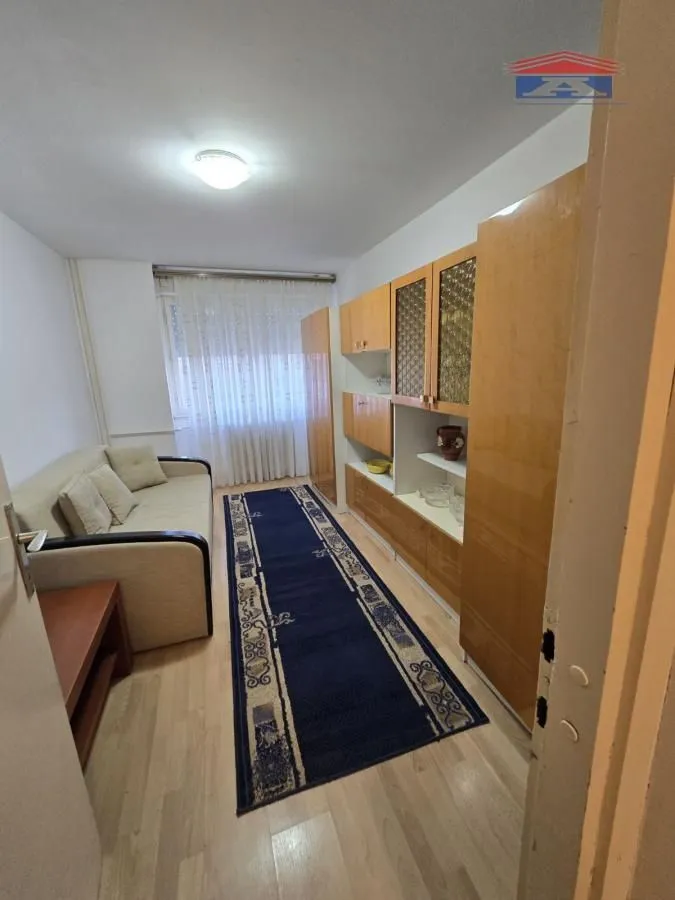 Dnevna soba sa garniturom za sedenje i drvenim ormarima.