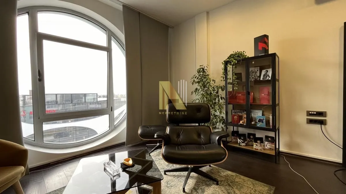 Living room with an armchair, a coffee table, and a large round window.