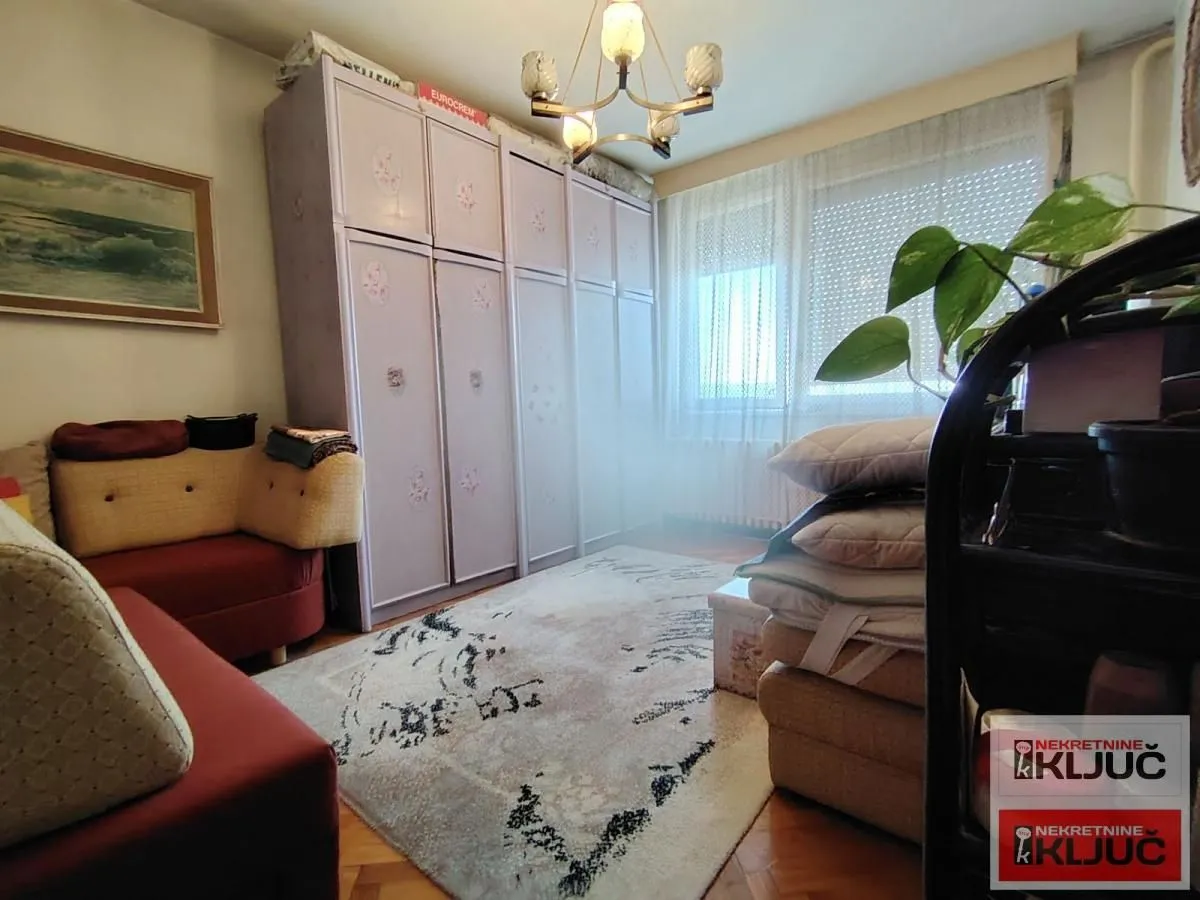 Dnevna soba sa garniturom, ormanom i prozorom.