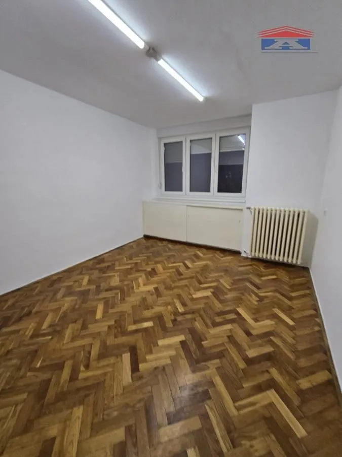 Empty room with hardwood parquet flooring and a radiator.
